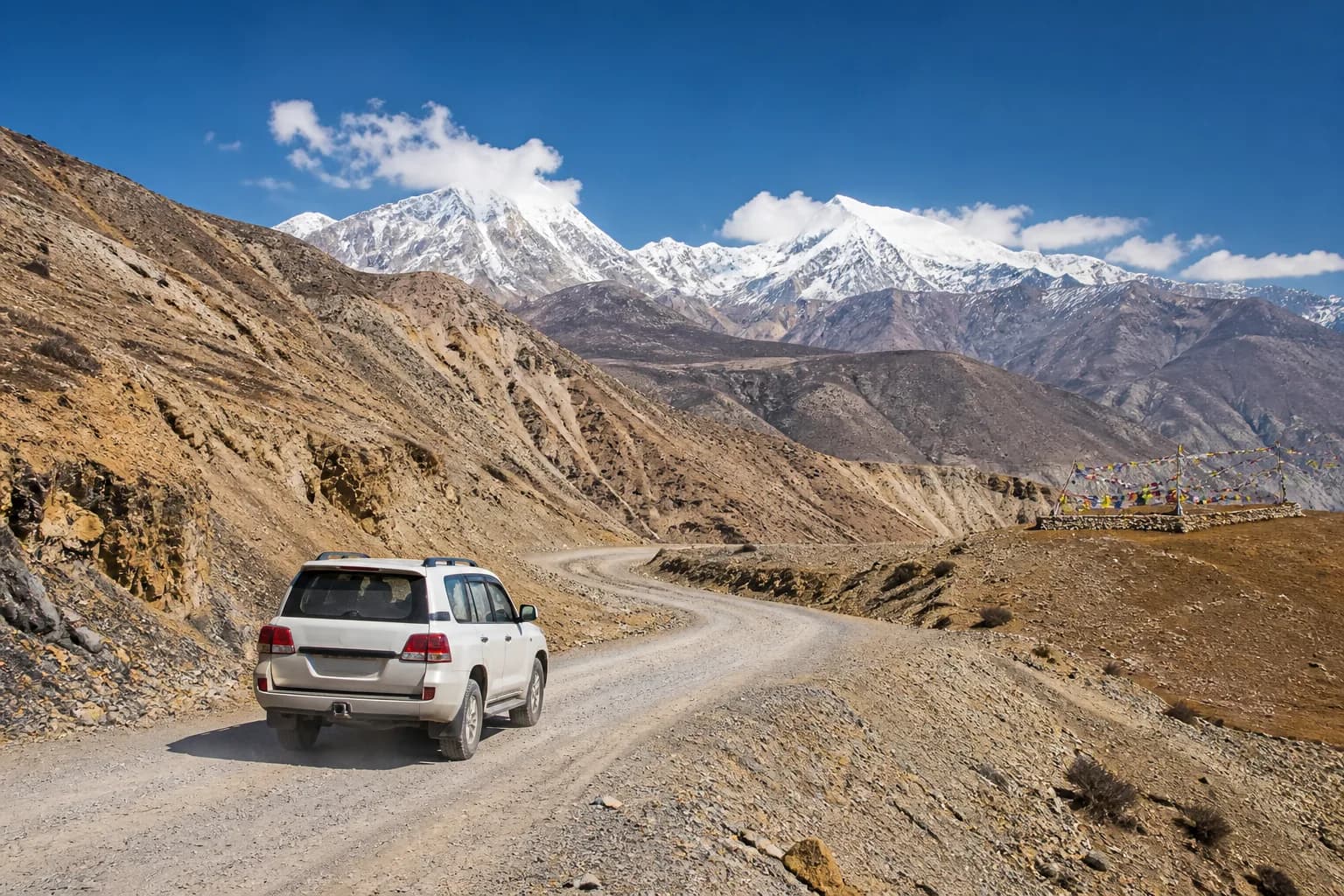 An SUV following the mountain road through Mustang toward Muktinath